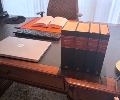 Bureau op het kantoor met een opengeslagen wetboek en de delen van het Handboek Burgerlijk Recht